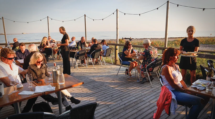Restaurang Marinan i Ystad – gäster äter middag på brygguteserveringen med Östersjön och solnedgången som fond.